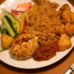 A full plate of pilau rice with salad, baked chicken breast and curry potatoes