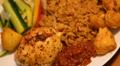 A full plate of pilau rice with salad, baked chicken breast and curry potatoes